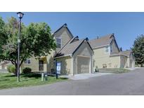 View of a tan two-story home with a two-car garage and a well-manicured lawn on a sunny day at 10359 W Fair Ave # F, Littleton, CO 80127