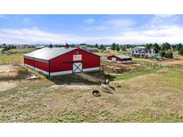 Bright red barn with a white accent, paddocks and horses creates a true country feel at 2190 Helen Ct, Parker, CO 80138