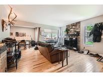 Relaxing living room featuring a stone fireplace, wood floors, and a comfortable leather sofa at 6213 Willow Ln, Boulder, CO 80301