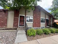 Red brick townhome featuring a secure screen door and well-kept front yard with decorative rock at 7020 W Portland Ave, Littleton, CO 80128