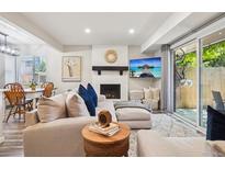 Inviting living room features a brick fireplace, large sectional sofa, and sliding glass door to the patio at 7995 E Mississippi Ave # F23, Denver, CO 80247