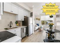 Bright kitchen featuring white cabinets, stainless steel appliances, and modern finishes open to living area at 5371 W 14Th Ave, Lakewood, CO 80214