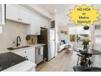 Modern kitchen with stainless appliances, white cabinets, stylish backsplash, and a view to the cozy living area at 5371 W 14Th Ave, Lakewood, CO 80214