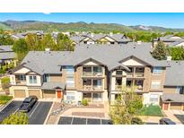 Inviting condo building featuring a gray roof, beige siding, balconies, and well-kept landscaping at 7433 S Quail Cir # 1924, Littleton, CO 80127