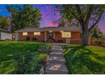 Charming brick home featuring a well-maintained lawn, mature trees, and a welcoming front entrance at 2724 S Ames Way, Denver, CO 80227