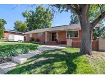 Charming brick home featuring a well-manicured lawn, stone walkway, and mature trees at 2724 S Ames Way, Denver, CO 80227