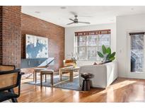 Modern living room featuring exposed brick wall, stylish furniture, and hardwood floors, bathed in natural light at 425 S Reed St, Lakewood, CO 80226