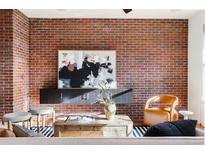 Stylish living room boasts a striking brick wall and sophisticated decor, plus sleek storage at 425 S Reed St, Lakewood, CO 80226