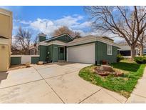 Charming green home featuring an attached two-car garage and well-maintained front yard with mature tree at 2675 S Deframe Cir, Lakewood, CO 80228