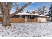 Charming brick home with a classic design and snow covered front yard at 10913 W 67Th Pl, Arvada, CO 80004