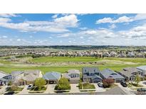An aerial view of a residential area with lush golf course and mountain views on a sunny, cloudy day at 11788 Mill Valley St, Parker, CO 80138
