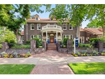 Charming brick home with a covered porch, balcony, landscaped front yard, and a beautiful brick walkway at 3309 E 7Th Ave Pkwy, Denver, CO 80206