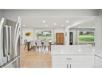 Open concept dining room with hardwood floors, large windows, and stainless steel refrigerator in view at 3285 N Monaco Pkwy, Denver, CO 80207