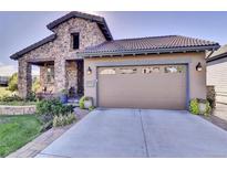 Charming home with a stone facade, landscaped front yard, and a two-car garage at 10553 Fairhurst Way, Highlands Ranch, CO 80126