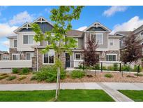 Charming townhouse showcasing a well-manicured lawn, stone accents, and appealing architectural details under a bright sky at 5745 S Buchanan Ct # C, Aurora, CO 80016