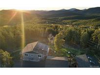Stunning aerial view of a home nestled in the mountains with solar panels and mature trees at 8 Sioux Trl, Evergreen, CO 80439