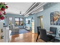 Bright living room featuring exposed ductwork, hardwood floors, and a cozy seating area with city views at 7700 E 29 Ave # 304, Denver, CO 80238
