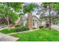 Charming home featuring a brick chimney, lush green lawn, and mature trees in a well-maintained front yard at 1148 S Ventura Cir # H, Aurora, CO 80017