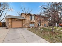 Charming stone facade home with a paved driveway and manicured front yard, perfect for curb appeal at 1390 S Ammons St, Lakewood, CO 80232