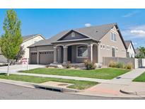 Charming home featuring manicured lawn, inviting front porch, and a three-car garage, set under a clear blue sky at 19802 E 54Th Ave, Denver, CO 80249