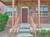 Charming brick home entrance featuring a red front door, concrete steps, and decorative railings at 5467 Zephyr Ct # 5467, Arvada, CO 80002