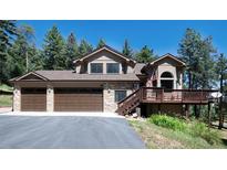 Charming two-story home featuring a three-car garage and a cozy front porch, nestled amongst lush trees at 8171 S Homesteader Dr, Morrison, CO 80465