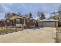 Charming single-story home featuring a brick exterior, large driveway, and detached garage with basketball hoop at 10705 Downing St, Northglenn, CO 80233