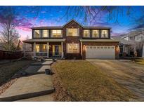 Charming two-story brick home featuring a covered porch, attached two car garage, and landscaped front yard at 5224 Snow Goose St, Brighton, CO 80601