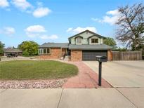 Charming two-story home with brick facade, dormer windows, well-manicured lawn and two car garage at 1460 Belmont Dr, Longmont, CO 80503