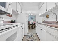 Galley kitchen featuring white cabinetry and laminate countertops, adjacent to dining area at 7375 E Quincy Ave # 204, Denver, CO 80237