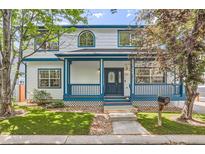 Charming two-story home with a covered front porch and beautiful blue accents on the trim and railings at 511 Noel Ave, Longmont, CO 80501
