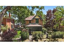 Charming brick home with lush landscaping, mature trees and a wrought iron fence at 3764 Newton St, Denver, CO 80211