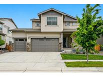 Two-story home showcasing a three-car garage, manicured lawn, and inviting curb appeal at 5779 Piney River Pl, Brighton, CO 80601