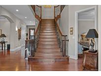 Grand staircase with ornate iron railings and hardwood steps leading to the upper level of the home at 1160 Monaco Pkwy, Denver, CO 80220