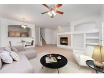 Open-concept living room with a cozy fireplace and adjacent kitchen space at 5255 Memphis St # 219, Denver, CO 80239