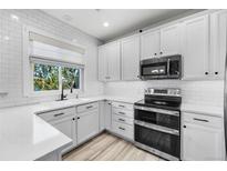 Bright kitchen with white cabinets, stainless steel appliances, and a window overlooking greenery at 13028 Grant W Cir # A, Thornton, CO 80241