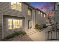 Inviting townhome showcases manicured landscaping, complemented by the warm hues of the sunset sky at 1311 Carlyle Park Cir, Highlands Ranch, CO 80129