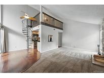 Bright living room features a spiral staircase, balcony, and an open floor plan at 9797 E Peakview Ave # C10, Englewood, CO 80111