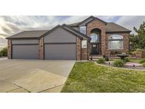 Beautiful brick and gray two-story home with a three-car garage and well-manicured lawn at 12693 W 82Nd Ln, Arvada, CO 80005