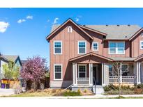 Charming two-story townhome featuring a covered porch and blossoming tree in front yard at 8951 E 59Th Pl, Denver, CO 80238