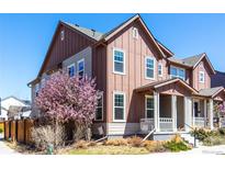 Inviting two-story home featuring a covered porch and a blossoming tree in the front yard at 8951 E 59Th Pl, Denver, CO 80238