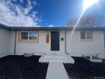 Charming front door and white brick exterior complemented by the beautiful landscaping in this lovely home at 7956 Joan Dr, Denver, CO 80221