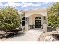 A stately home exterior showcasing a stone facade, archway and double door entry at 8937 Little Raven Trl, Niwot, CO 80503