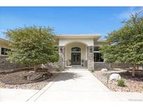 Inviting stone and stucco front entrance with arched doorway and lush landscaping at 8937 Little Raven Trl, Niwot, CO 80503
