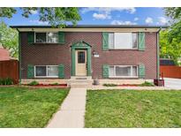 Charming two-story brick home with lush green lawn, tidy garden beds, and bright green shutters at 11855 Humboldt Dr, Northglenn, CO 80233
