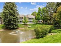 Scenic view of a pond with a fountain, surrounded by lush greenery and a building with balconies at 8335 Fairmount Dr # 9-201, Denver, CO 80247