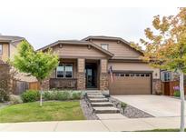 Charming home boasts a covered front porch, well-manicured lawn, and an attached two-car garage at 25120 E Maple Pl, Aurora, CO 80018