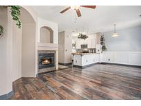 Open concept living area with a cozy fireplace, hardwood floors, and a view of the kitchen at 14400 Albrook Dr # 43, Denver, CO 80239