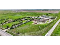 Expansive aerial view of a multi-building property surrounded by lush greenery and agricultural fields at 1614 N Manila Rd, Bennett, CO 80102