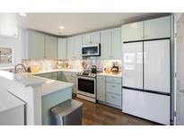 Charming kitchen with stainless steel appliances, tiled backsplash, and light blue cabinets at 12831 Mayfair Way # F, Englewood, CO 80112